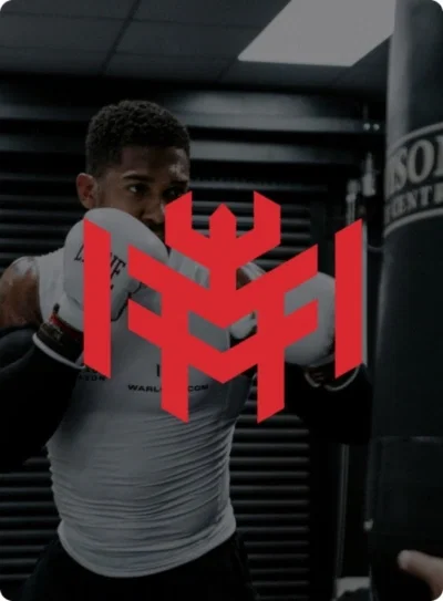 Athlete shadow boxing in gym with red logo overlay on white fight shorts and punching bag.